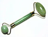 Green jade facial roller on a white background
