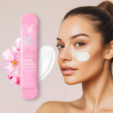 Woman with sunscreen on her face next to a pink sunscreen bottle and sakura flower.